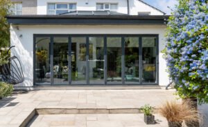 Stylish, closed, bifold doors with plants in spring, summer, revealing interior of a designer, lifestyle, kitchen diner room.