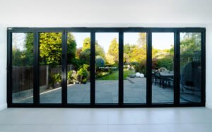 View through closed bifold doors of attractive garden and patio in summer.