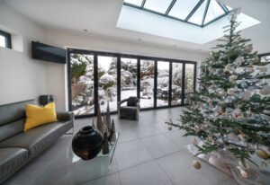 Bifold doors and skylight at Christmas / Xmas with luxury room, Christmas tree and view to garden with snow.